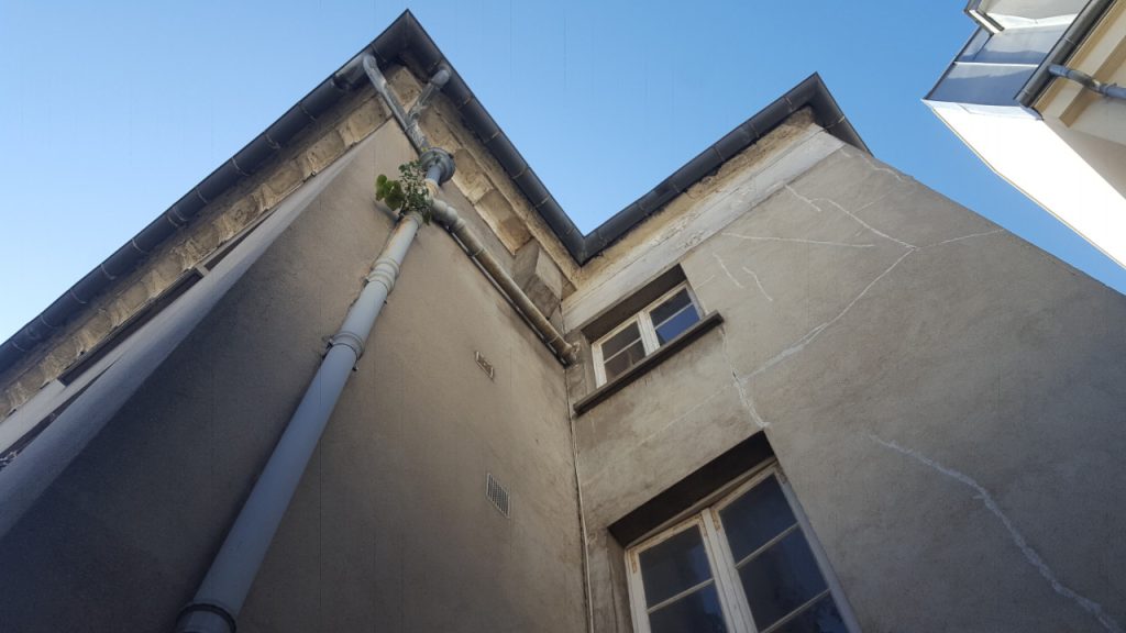 Façade d’immeuble fissurée avec descente d’eau pluviale VERTIKAL