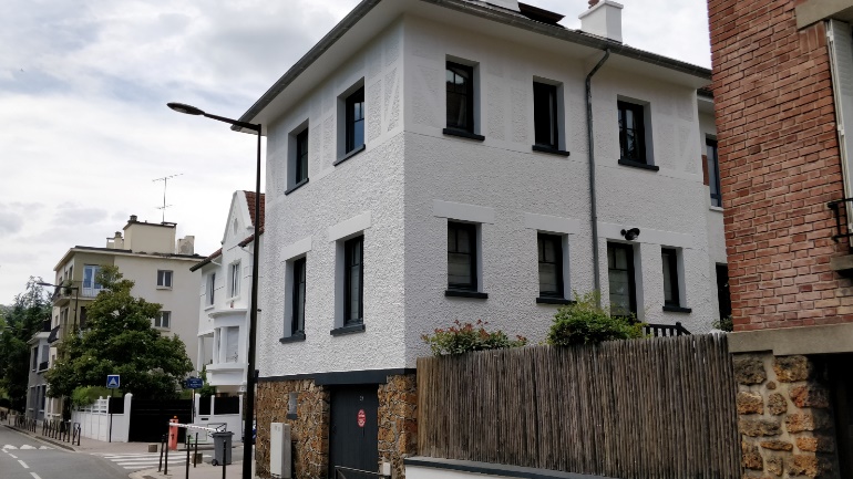 Maison VERTIKAL à façade blanche rénovée avec encadrements noirs
