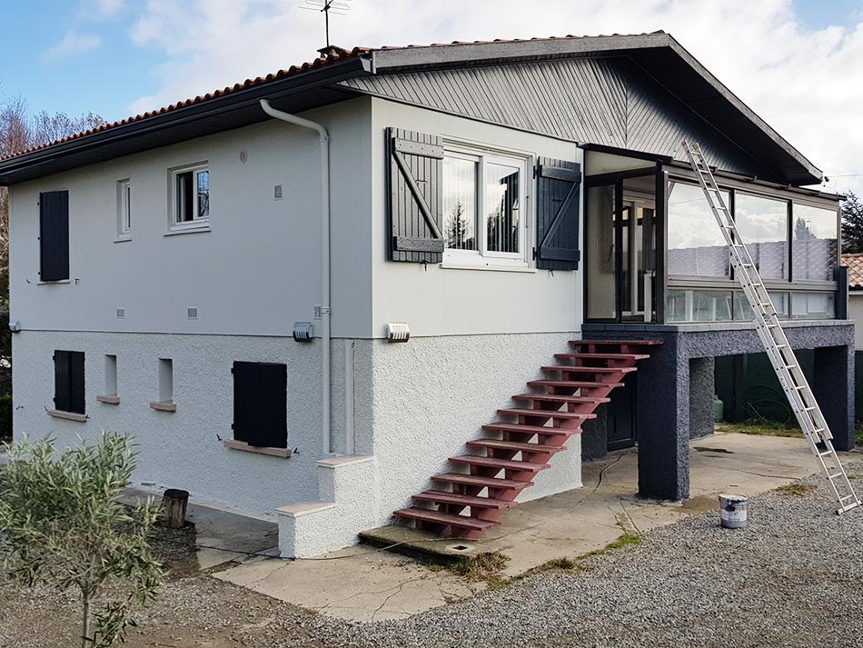 Façade de maison rénovée avec volets gris et véranda VERTIKAL