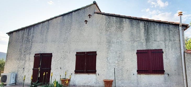 Maison avec volets marron, style VERTIKAL, murs en béton.