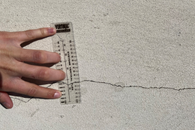 Main tenant une règle VERTIKAL contre une fissure sur un mur.